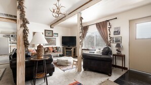 Een woonkamer met twee banken, een televisie en een open haard.