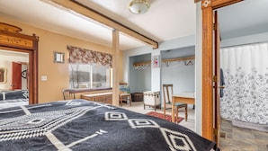 Een slaapkamer met een bed, een houten stoel, een tafel en een raam.