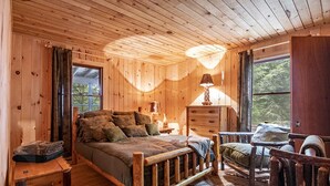 A cozy wooden cabin bedroom with a bed, dresser, and chair. - Luxury Cabin on the Lake & In The Trees (Saranac Lake)