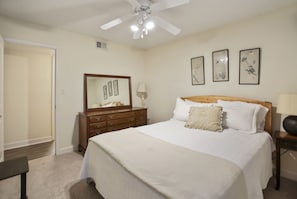 Quarto com cama, penteadeira, espelho e obras de arte nas paredes.