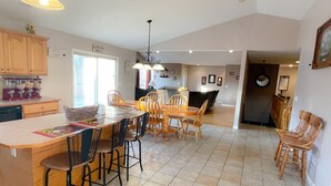 A spacious kitchen with a large island, wooden chairs, and a dining table. There are cabinets, a refrigerator, and a window providing natural light. - Windrock Retreat (Oliver Springs)