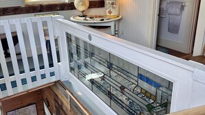 Un escalier avec une rampe en bois, un mur blanc avec une fenêtre et une lampe posée sur une petite table.