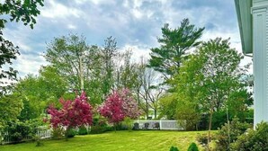 Une pelouse bien entretenue, agrémentée de diverses plantes et d’un petit jardin orné d’une sphère bleue décorative.