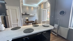 Una cocina moderna con una isla central, un comedor con mesa y sillas, y vistas al exterior por una ventana.