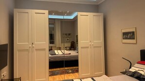 Un dormitorio con cama, armario y espejo.
