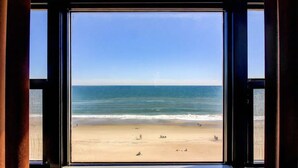 A beach view through a window with a clear sky. - Oceanfront condo at Summer Winds Resort in Indian Beach, NC (Indian Beach)