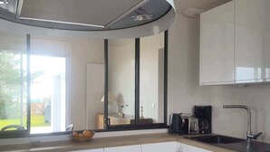 Une cuisine moderne avec des meubles blancs, un plan de travail noir, une cuisinière encastrée et une fenêtre donnant sur un jardin.