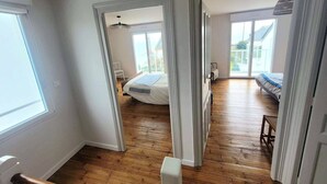 Une pièce spacieuse avec un plancher en bois, un lit, une chaise et une grande fenêtre.