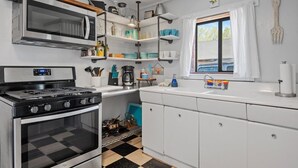 Une cuisine équipée d’une cuisinière, d’un four, d’un four à micro-ondes et d’étagères où sont rangés la vaisselle et les ustensiles de cuisine.