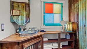 Une salle de bain rustique avec un meuble-lavabo en bois, un miroir et une fenêtre ornée de vitraux colorés.