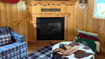 A cozy room with a fireplace, a television, a plaid sofa, and a Christmas tree.