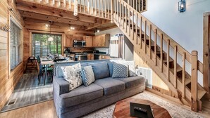 A modern log cabin interior with a wooden staircase, a dining area, and a kitchen. - Gorgeous Views! Secluded | HotTub | Quiet & Cozy (Townsend)