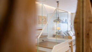 A modern interior with a glass staircase, a dining area with a table and chairs, and a hanging light fixture. - Casa Felicidad, Air Conditioning, Sea View - Puerto del Carmen, Lanzarote (Puerto del Carmen)