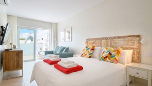A modern hotel room with a large bed, a wooden nightstand, a desk, and a chair. - Casa Felicidad, Air Conditioning, Sea View - Puerto del Carmen, Lanzarote (Puerto del Carmen)