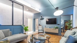 Un salon moderne avec un canapé, des fauteuils, une table basse et un téléviseur fixé au mur.