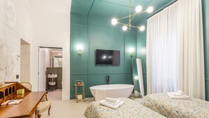 Une chambre moderne avec un grand lit, une commode en bois, une baignoire et un téléviseur.