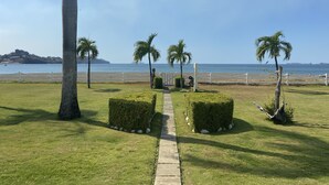 Un sentier qui mène à une plage bordée de palmiers et d’où l’on a une vue dégagée sur l’océan.