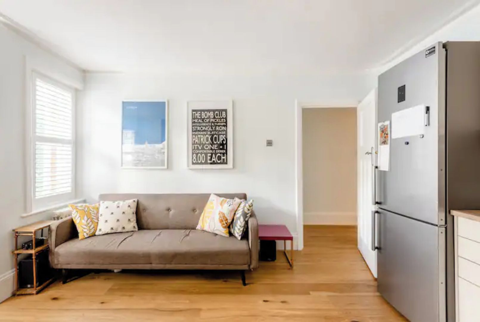 A modern living room with a sofa, a small table, and a refrigerator.
