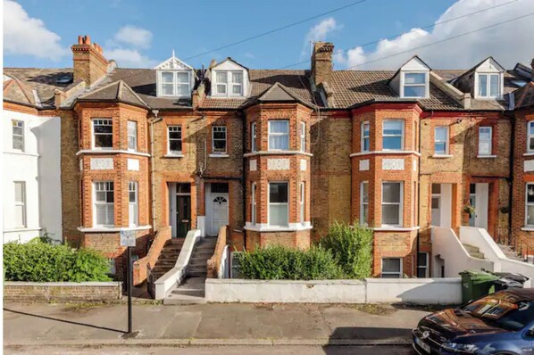 Row of charming houses with brick construction and pitched roofs, featuring multiple windows and a central staircase.