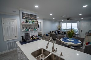 A modern kitchen with a built-in sink, a coffee bar, and a dining area with a round table and chairs. - Beachfront! Gorgeous! Playa Tortuga (Galveston)