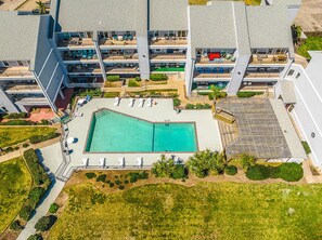 An aerial view of a hotel with a central swimming pool, multiple balconies, and surrounding greenery. - Beachfront! Gorgeous! Playa Tortuga (Galveston)