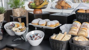 Buffet com diversos alimentos, incluindo doces, pães e acompanhamentos.