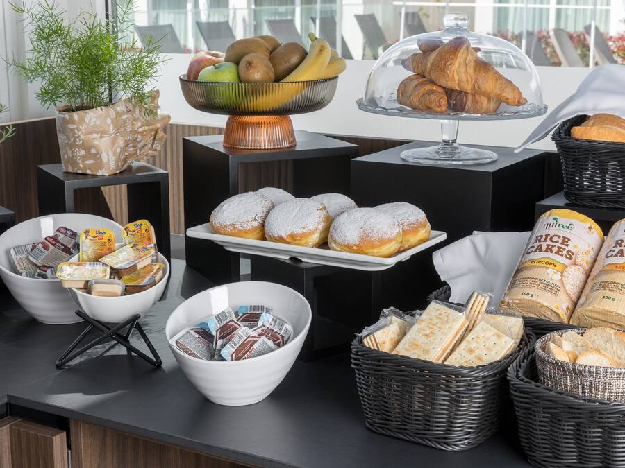 Un bufé con diversos alimentos, incluyendo pasteles, pan y salsas.