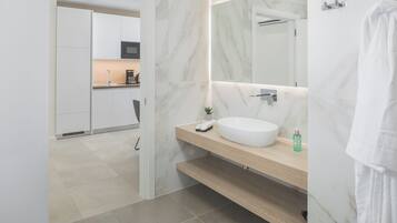 A modern bathroom with a white sink, marble walls, and a wooden vanity.