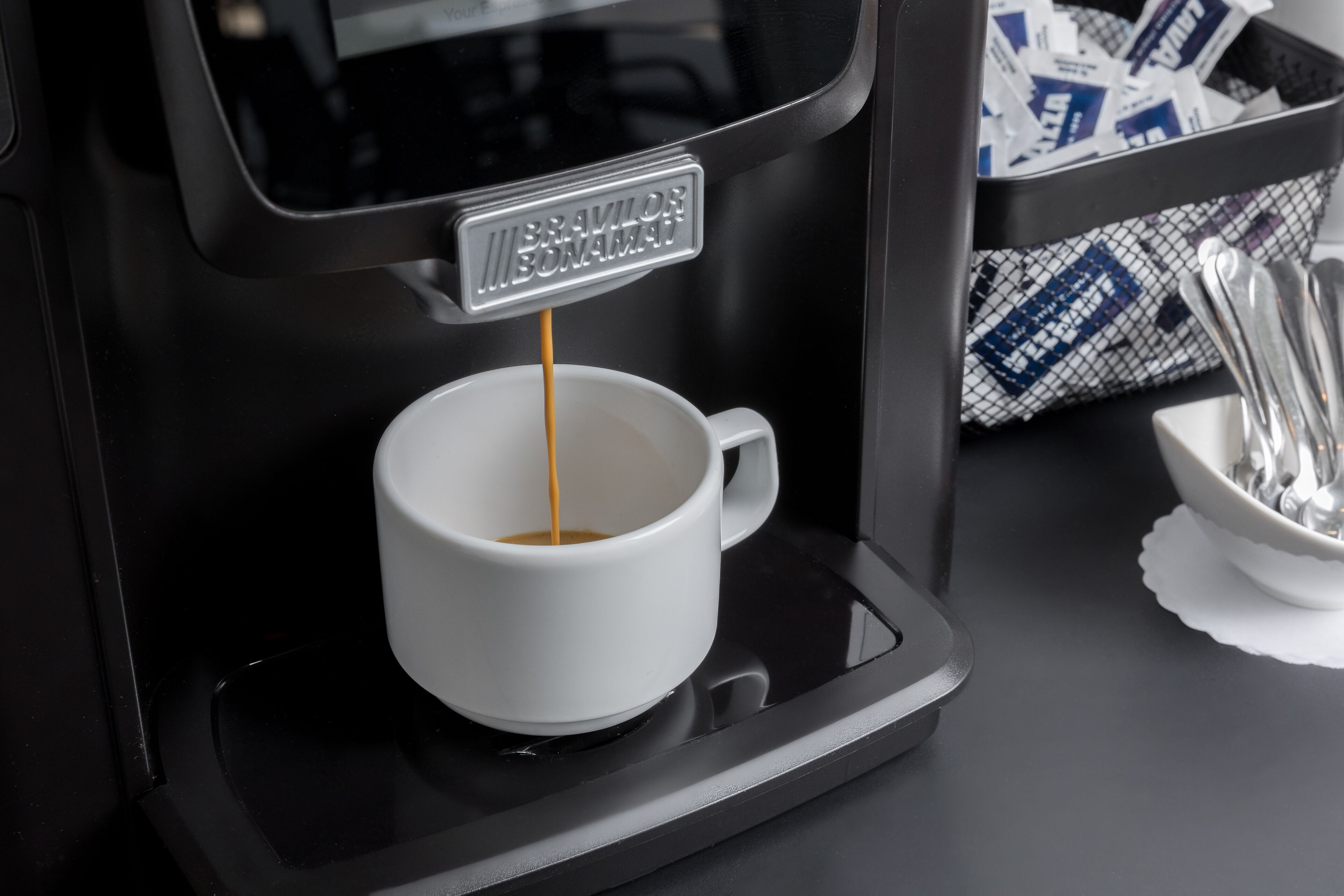 A coffee machine dispensing coffee into a white cup.