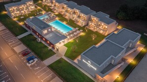 Um hotel moderno com várias unidades, piscina e áreas externas bem iluminadas.