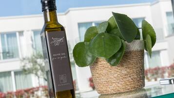 A bottle of olive oil and a potted plant on a glass table with a building in the background.