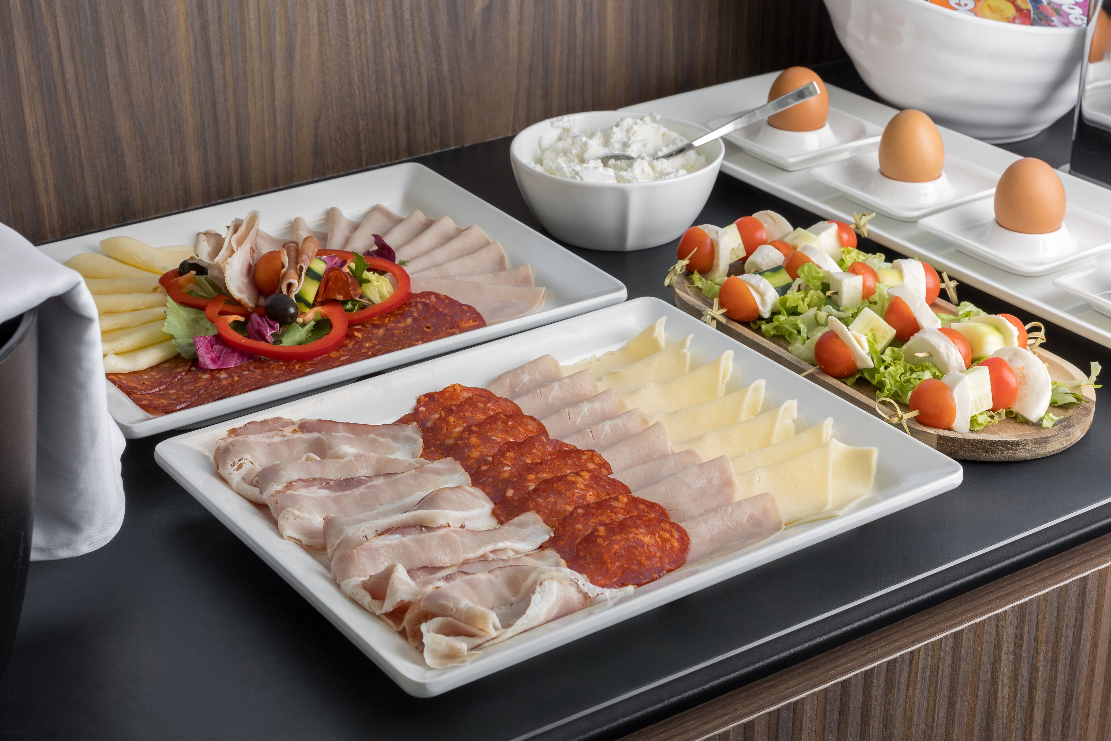 A buffet with various food items including sliced meats, cheeses, and vegetables.