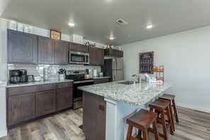 Une cuisine moderne avec des meubles en bois foncé, des appareils électroménagers en acier inoxydable et un plan de travail en granit.