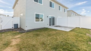 Une maison à deux étages avec un patio couvert et une cour arrière clôturée.