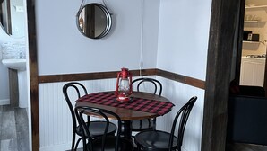 Un comedor con una mesa de madera y cuatro sillas, un farol rojo y una lámpara colgante.