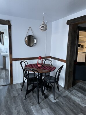 Un comedor con una mesa de madera y cuatro sillas, un farol rojo y una lámpara colgante.