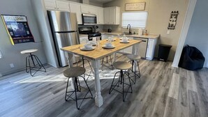 A modern kitchen with a central island, white cabinetry, stainless steel appliances, and a wooden floor.