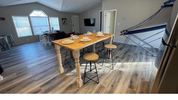 A spacious living area with a wooden dining table, two chairs, and a hammock.