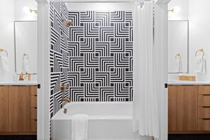 A bathroom with a black and white geometric tile backsplash, a white bathtub, and wooden cabinets. - Alexander Dr 7 Minutes to Northshore (Chattanooga)