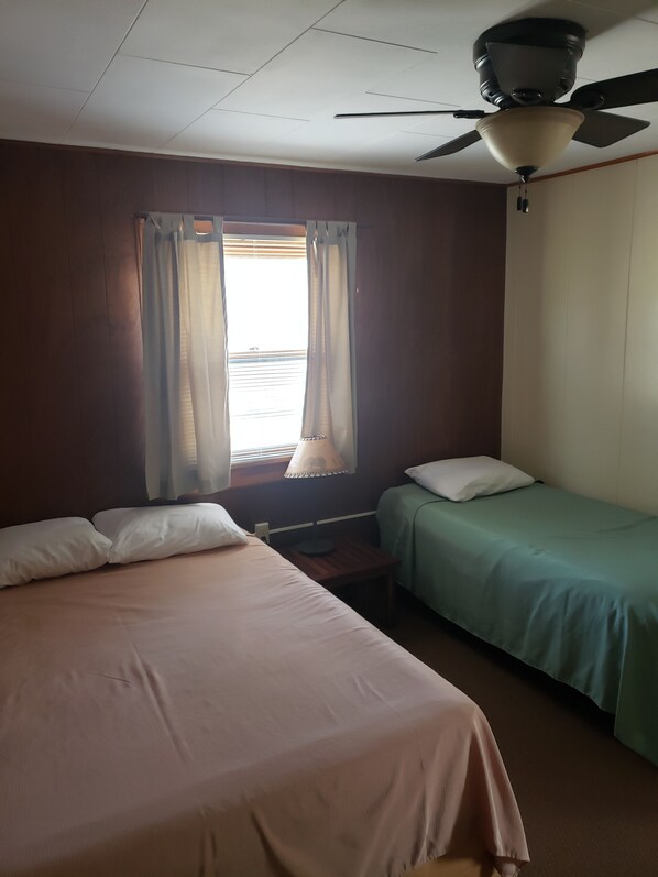 A room with two beds, one larger and one smaller, a ceiling fan, and a window with curtains. - lazy bear cabins (South Fork)
