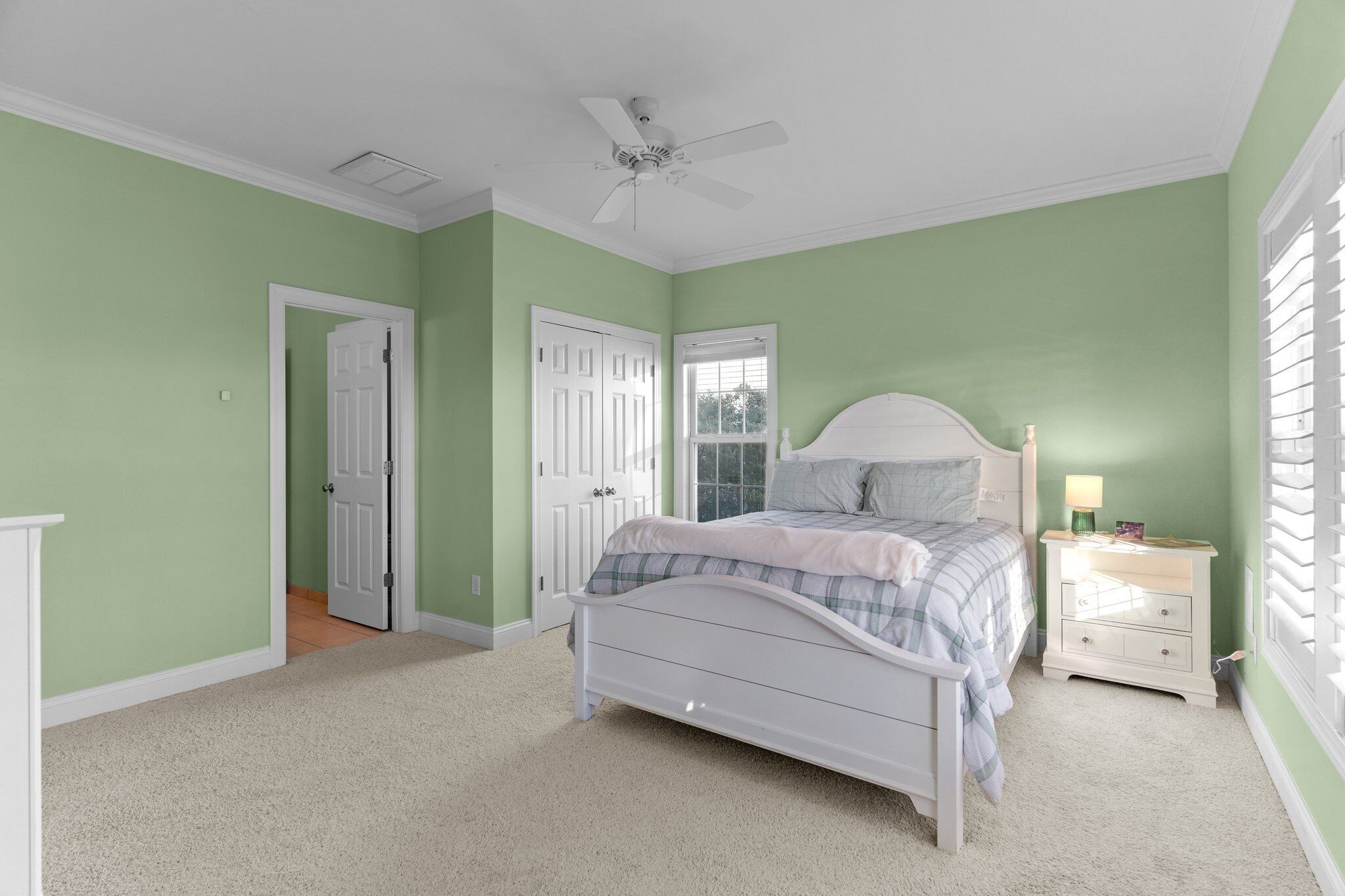 A bedroom with a bed, nightstand, and a ceiling fan.