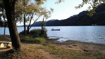 Vista del lago con un bote en el agua, árboles y cielo despejado.