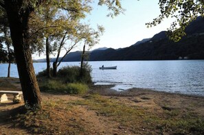 Vista del lago con un bote en el agua, árboles y cielo despejado.