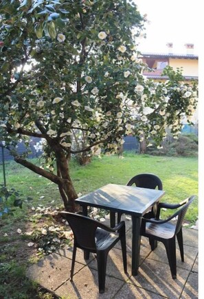 Un área de estar al aire libre con una mesa y sillas bajo un árbol en flor.