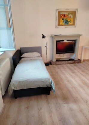 Un dormitorio con cama, televisión, chimenea y un cuadro en la pared.