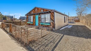 Eine kleine Holzhütte mit Veranda, einem Schotterweg und einem umzäunten Garten.