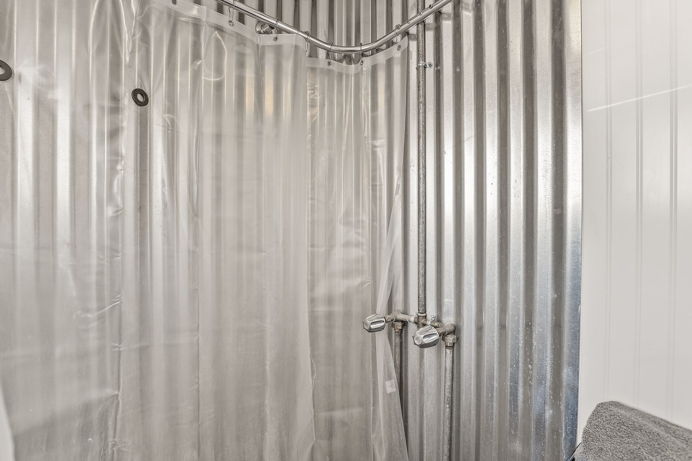 Un cerramiento de ducha con pared de metal corrugado y un cabezal.