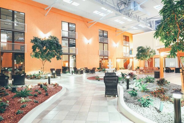 A spacious indoor courtyard with a central fountain, surrounded by seating areas and potted plants.