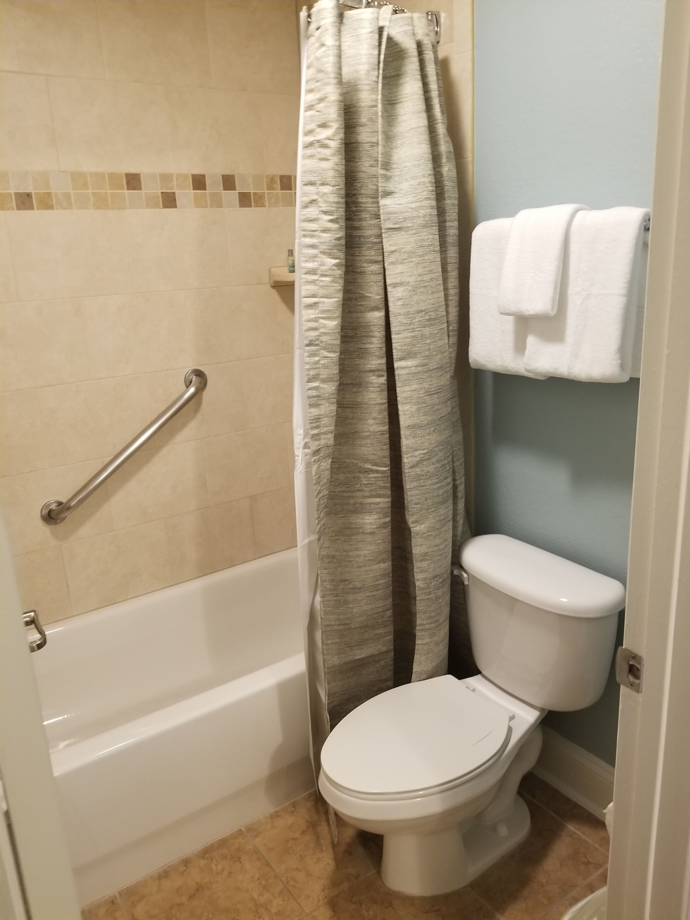 Een badkamer met een bad, toilet en douchegordijn.