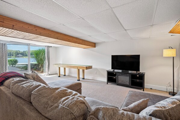 A modern living room with a large window, a flat-screen TV, a wooden bench, and a sofa.